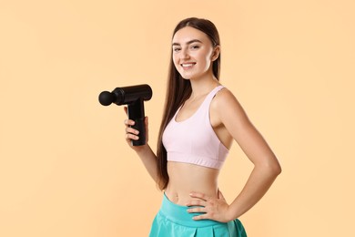 Young woman with percussive massager on beige background