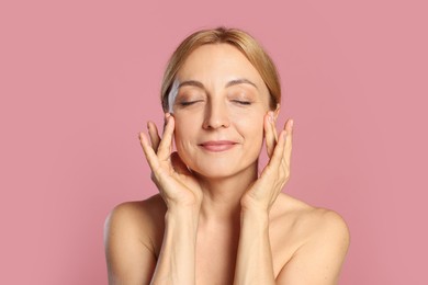 Portrait of beautiful woman with healthy skin on pink background