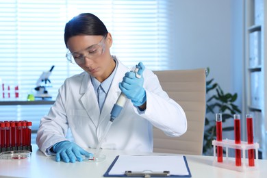 Photo of Laboratory testing. Doctor dripping blood sample into Petri dish at table indoors