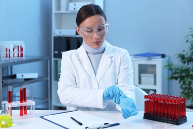 Laboratory testing. Doctor putting on gloves at table indoors