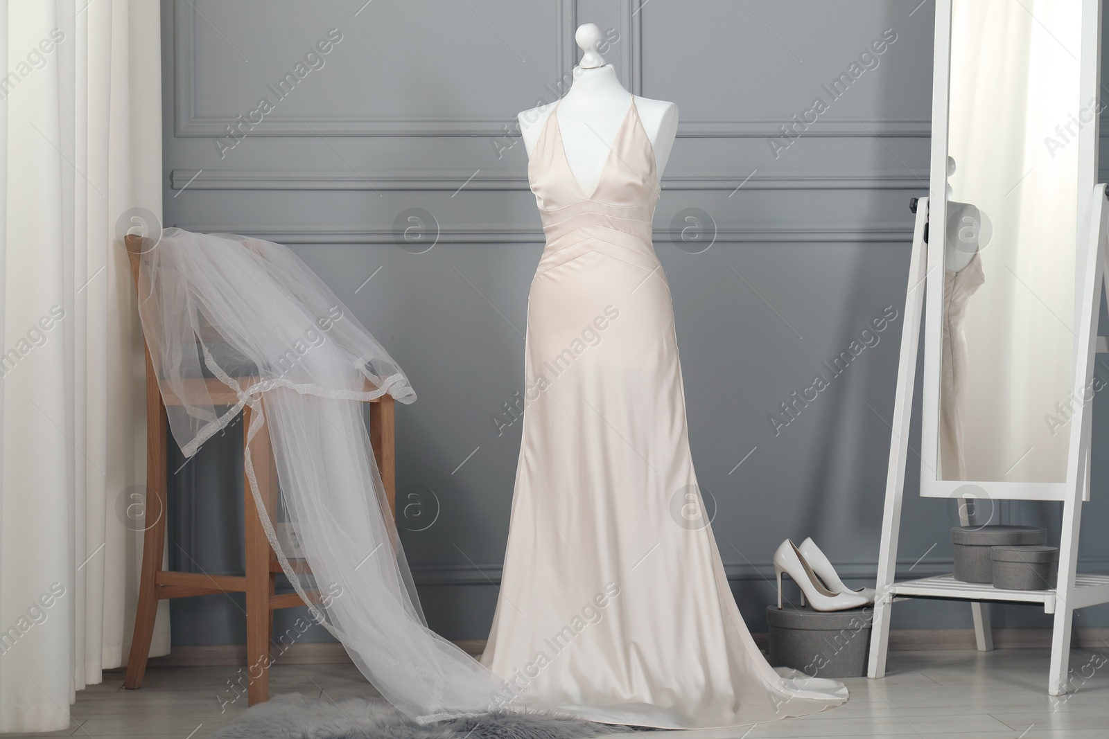 Photo of Beautiful wedding dress on mannequin, veil and shoes in boutique