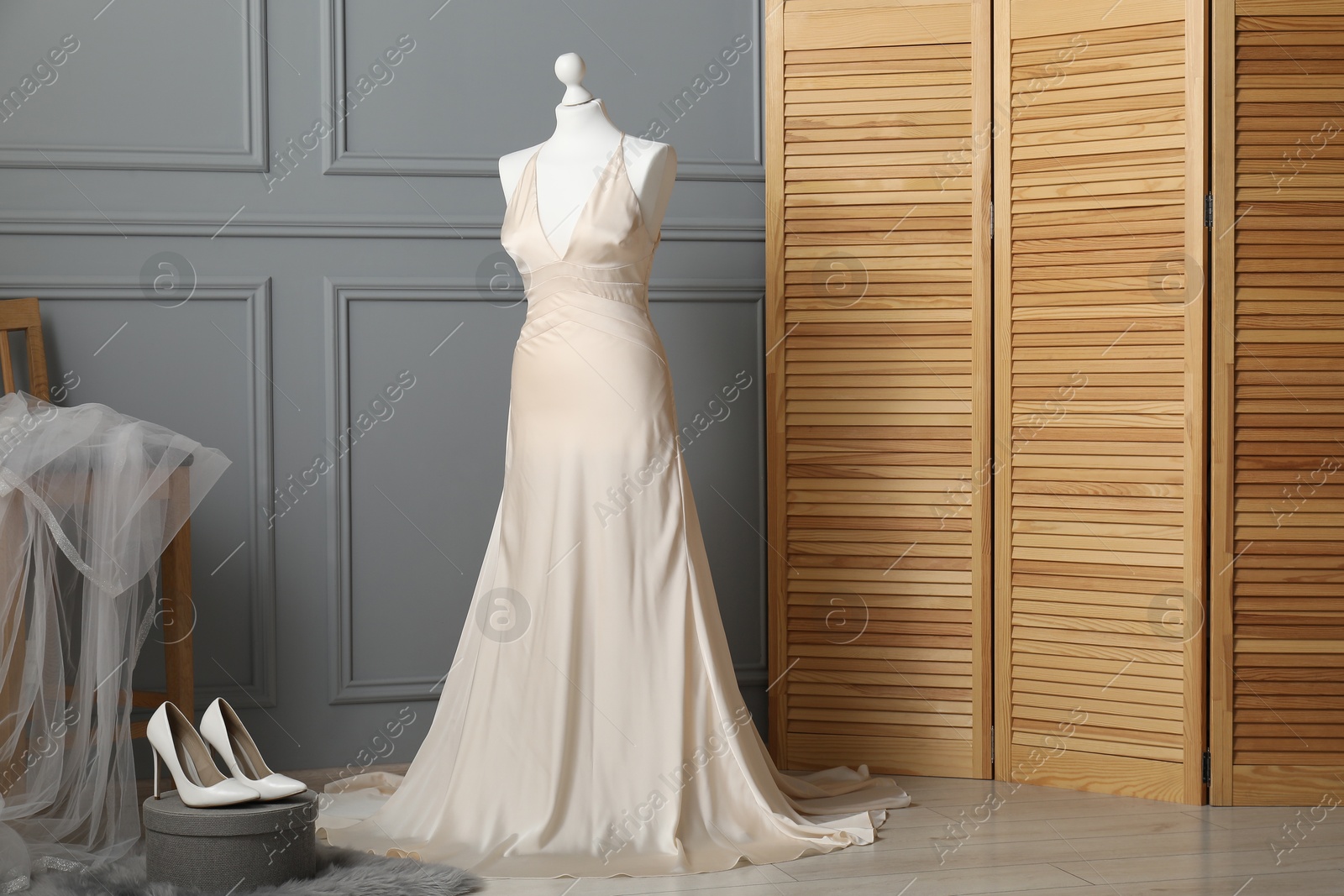 Photo of Beautiful wedding dress on mannequin, veil and shoes in boutique