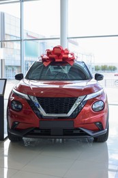 Photo of Luxury vehicle. New modern red car with bow in salon