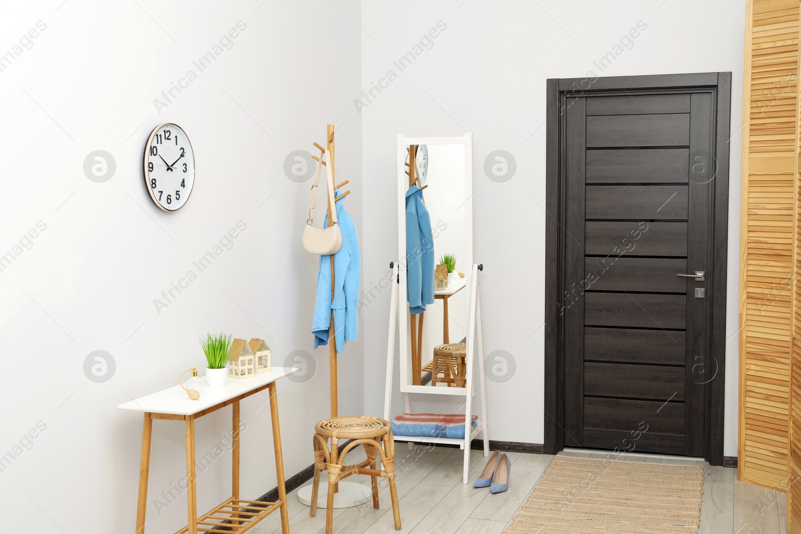 Photo of Clothing rack, mirror, storage bench and clothes in hallway