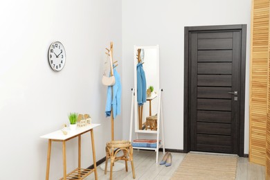 Photo of Clothing rack, mirror, storage bench and clothes in hallway