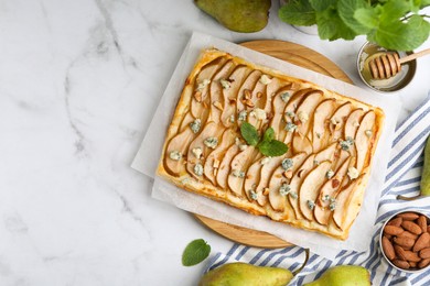 Photo of Delicious puff pastry tart with pears, almond, mint and blue cheese on white marble table, flat lay. Space for text