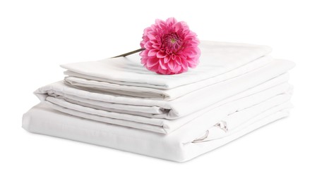 Photo of Stacked bed linens and pink flower on white background