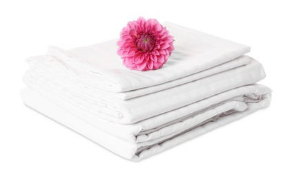 Photo of Stacked bed linens and pink flower on white background