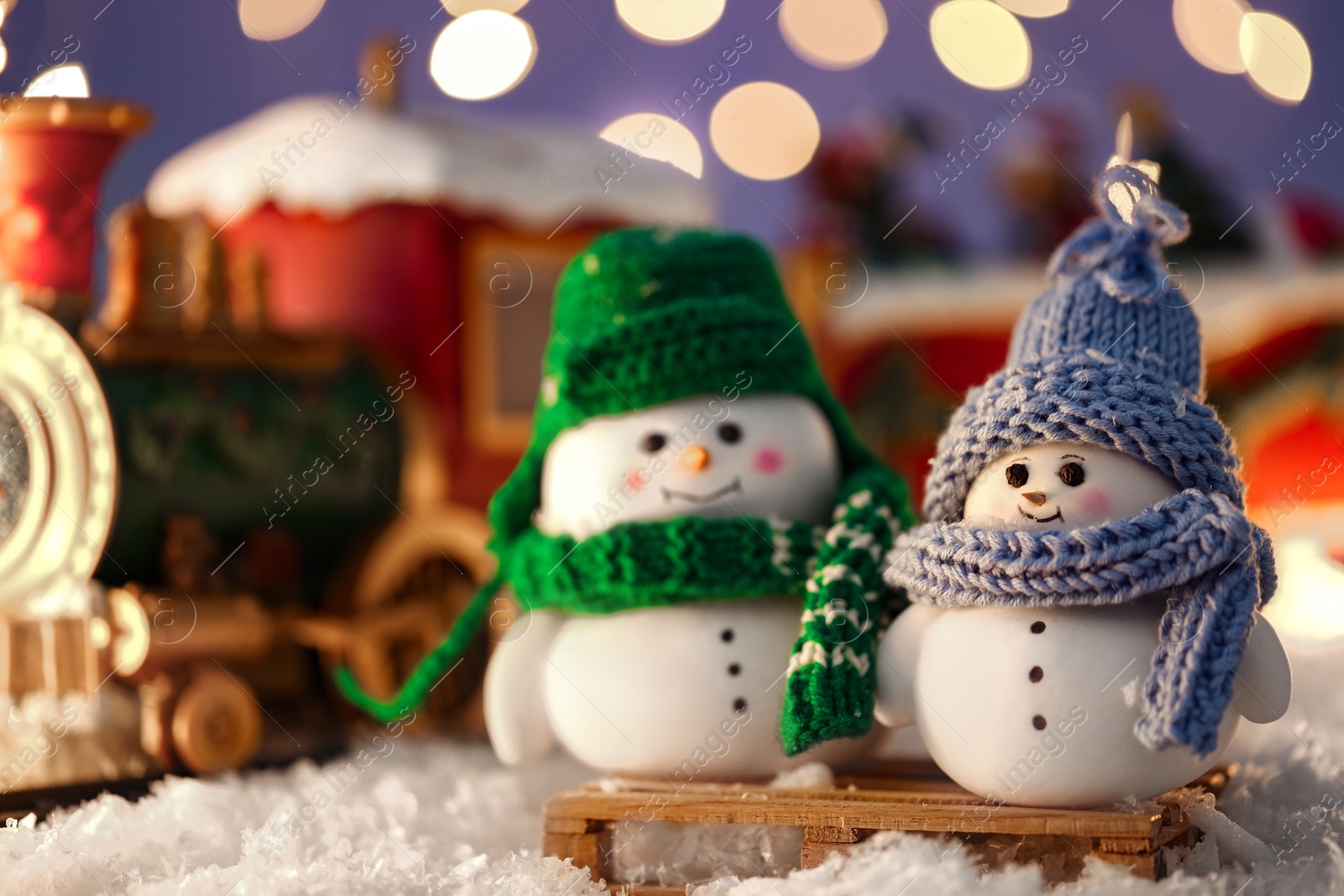 Photo of Cute decorative snowmen on artificial snow against blurred background, closeup