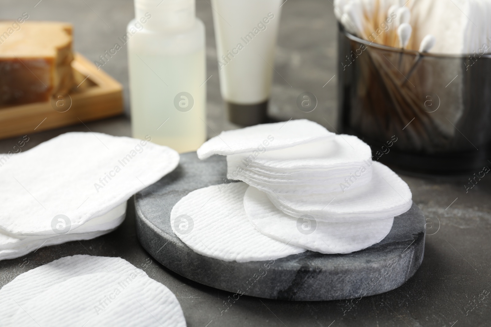 Photo of Many cotton pads on grey textured table, closeup