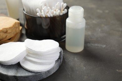 Photo of Many cotton pads and other toiletries on grey textured table, closeup