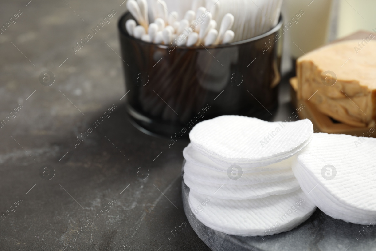 Photo of Many cotton pads and swabs on grey textured table, closeup. Space for text