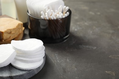 Photo of Many cotton pads and swabs on grey textured table, closeup. Space for text