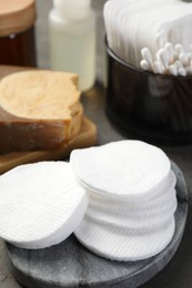 Photo of Many cotton pads and other toiletries on grey table