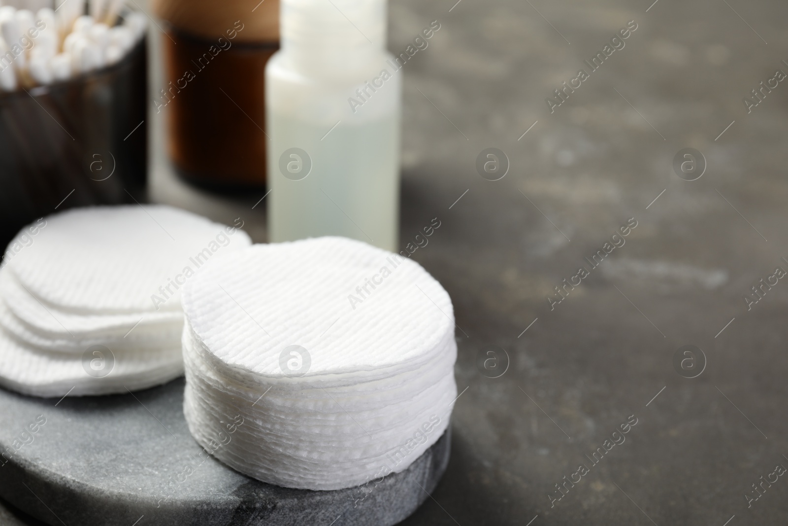 Photo of Many cotton pads on grey textured table, closeup. Space for text