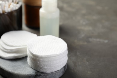 Photo of Many cotton pads on grey textured table, closeup. Space for text