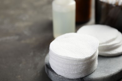 Photo of Many cotton pads on grey textured table, closeup. Space for text