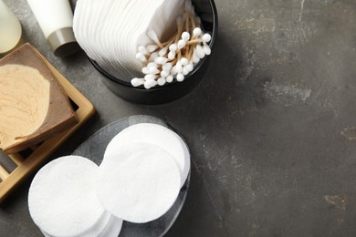 Photo of Many cotton pads and swabs on grey textured table, flat lay. Space for text