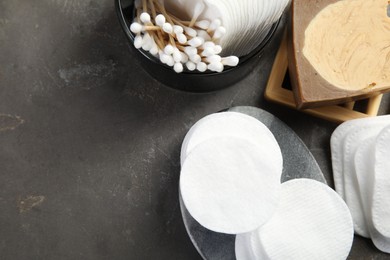 Many cotton pads and swabs on grey textured table, flat lay. Space for text