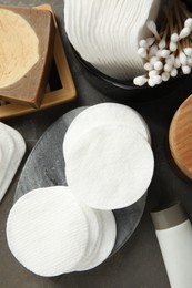 Photo of Many cotton pads and other toiletries on grey table, flat lay