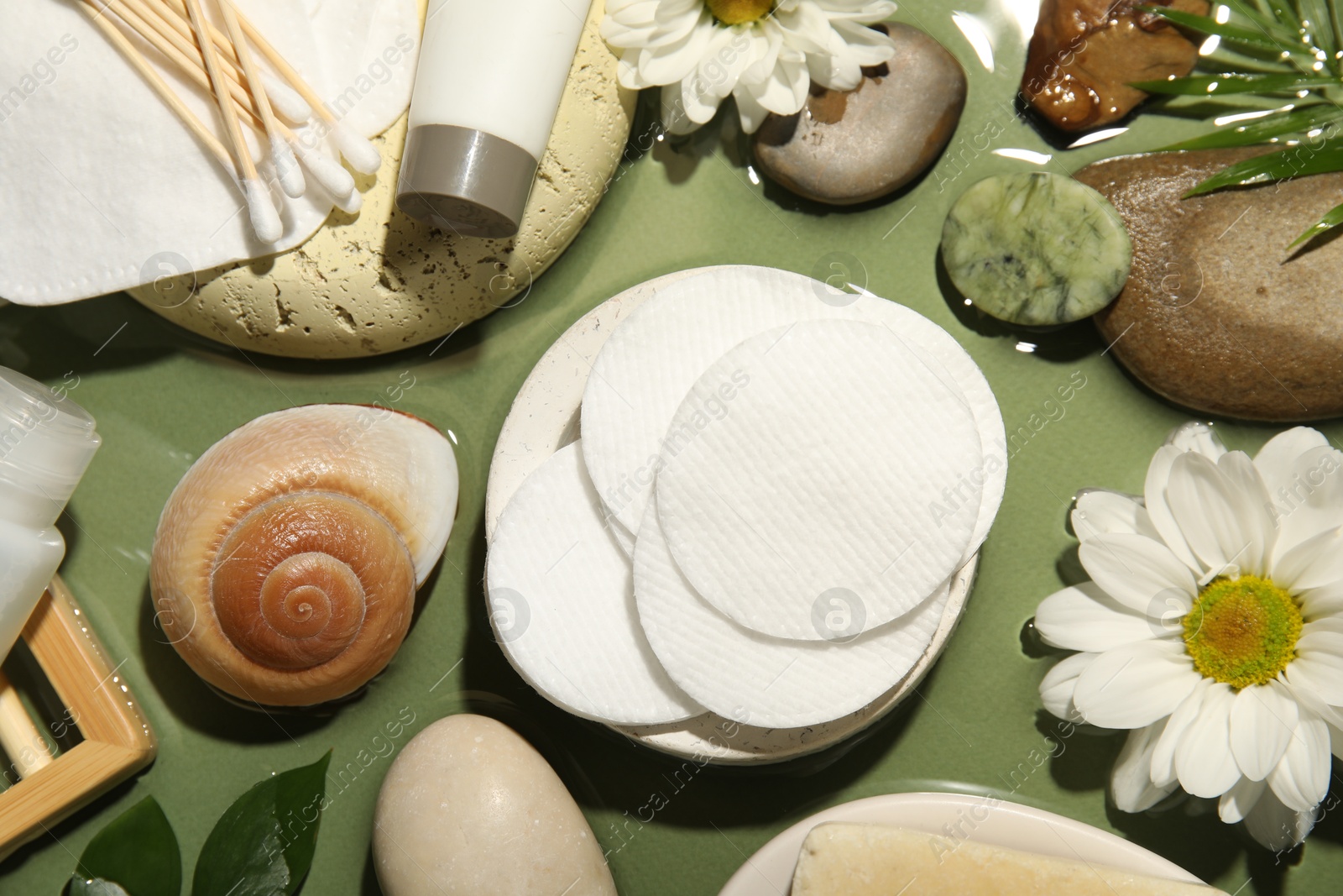 Photo of Flat lay composition with cotton pads and swabs on green table