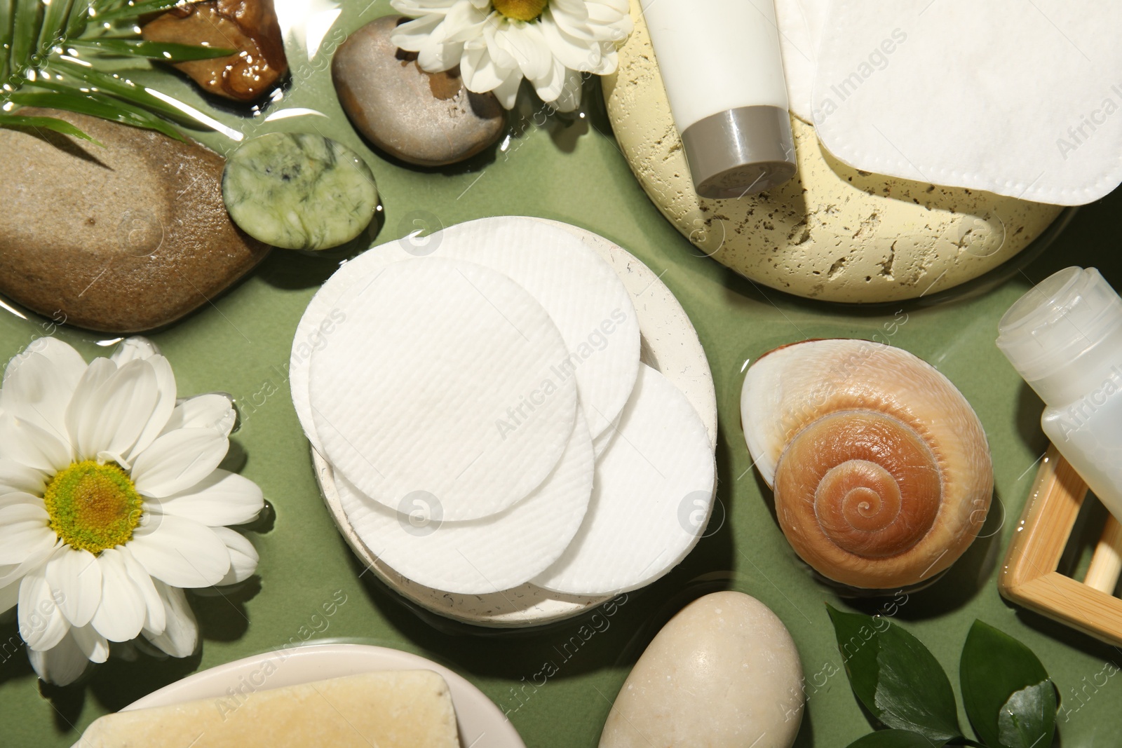 Photo of Flat lay composition with cotton pads and swabs on green table