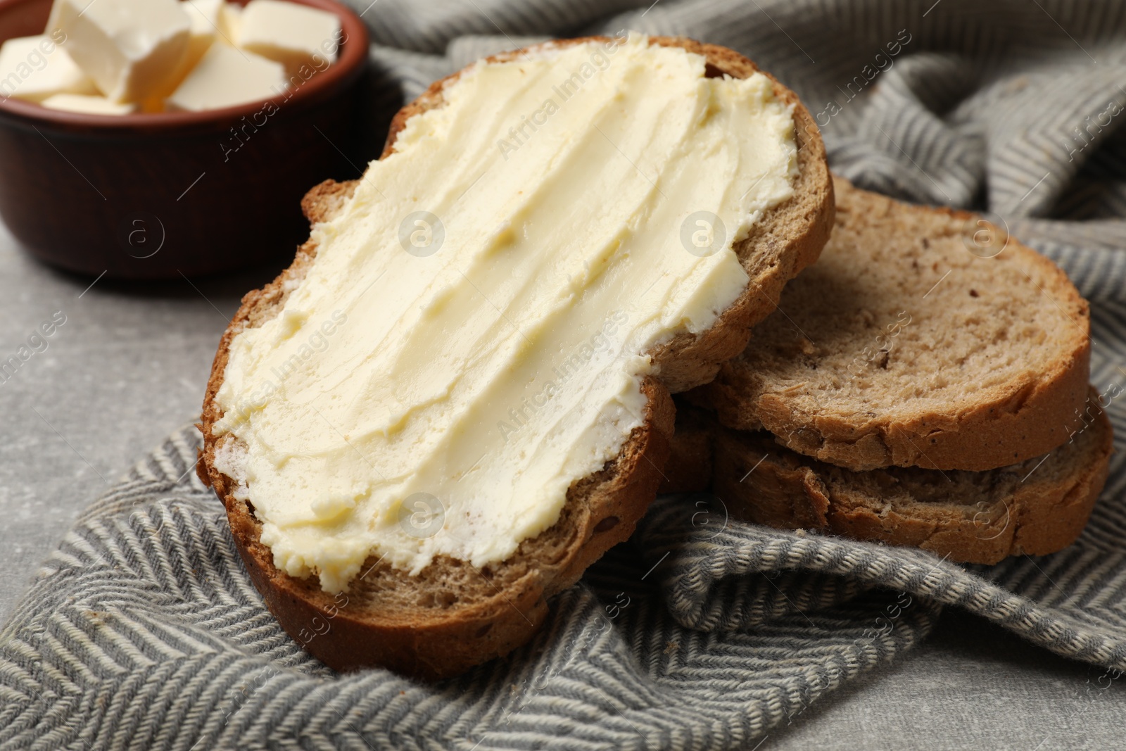 Fresh bread with butter on grey table, closeup Photo of Fresh bread with butter on grey table, closeup
