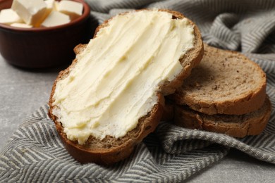 Photo of Fresh bread with butter on grey table, closeup