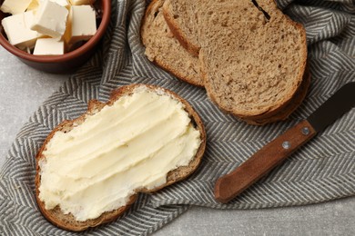 Photo of Fresh bread with butter and knife on grey table, flat lay