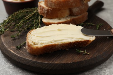 Photo of Fresh bread with butter and knife on grey table, closeup