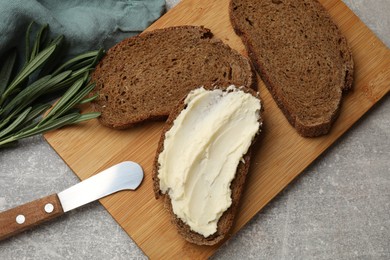 Photo of Fresh bread with butter and knife on grey table, flat lay