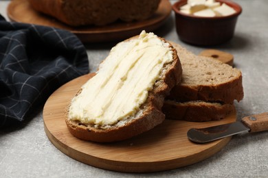 Photo of Fresh bread with butter and knife on grey table, closeup