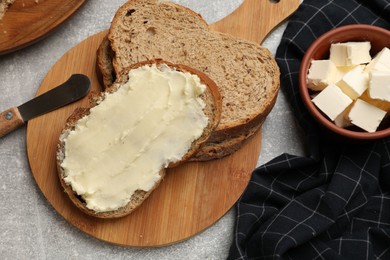 Photo of Fresh bread with butter and knife on grey table, flat lay