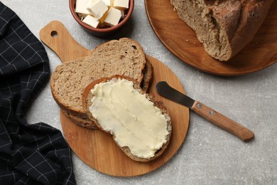 Photo of Fresh bread with butter and knife on grey table, flat lay