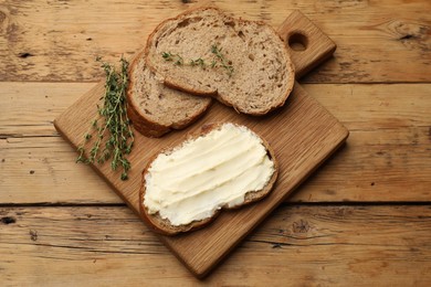 Photo of Fresh bread with butter and thyme on wooden table, top view