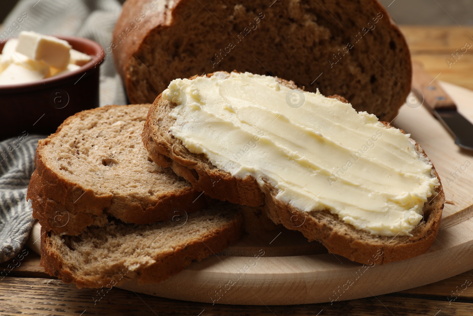 Photo of Fresh bread with butter on wooden table, closeup