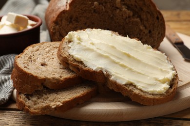 Photo of Fresh bread with butter on wooden table, closeup