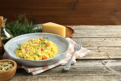 Photo of Delicious pumpkin risotto served on wooden table. Space for text