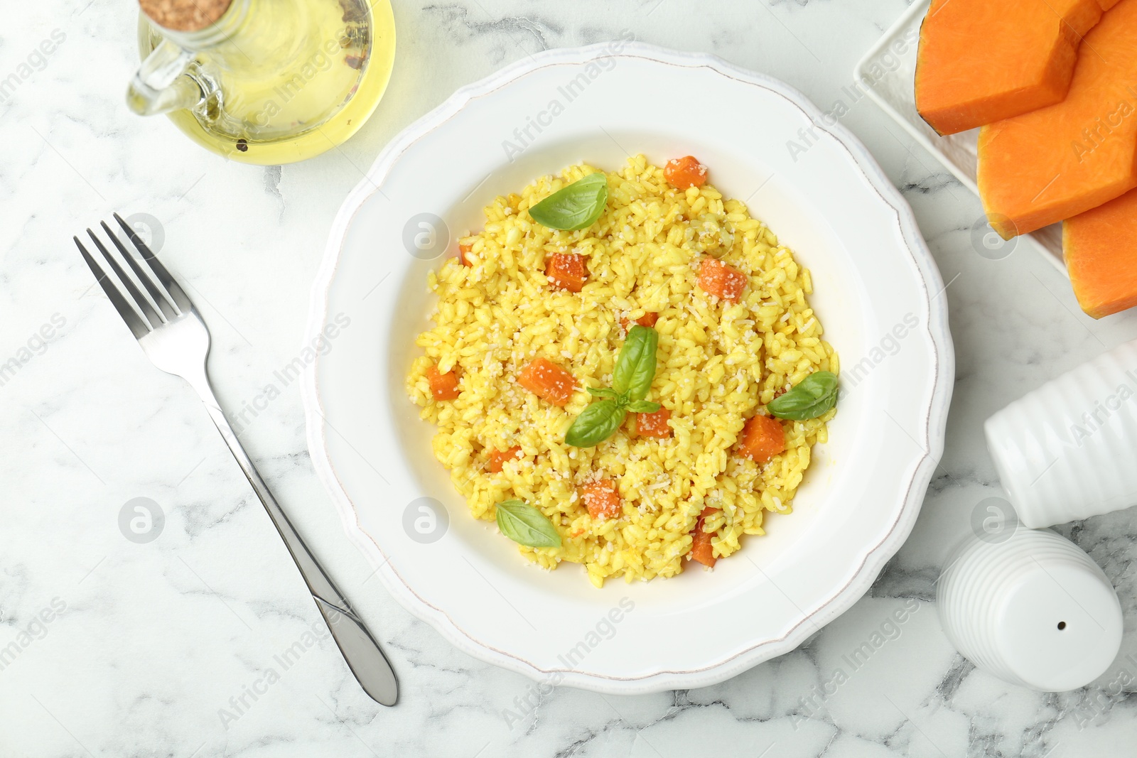 Photo of Delicious pumpkin risotto served on white marble table, flat lay