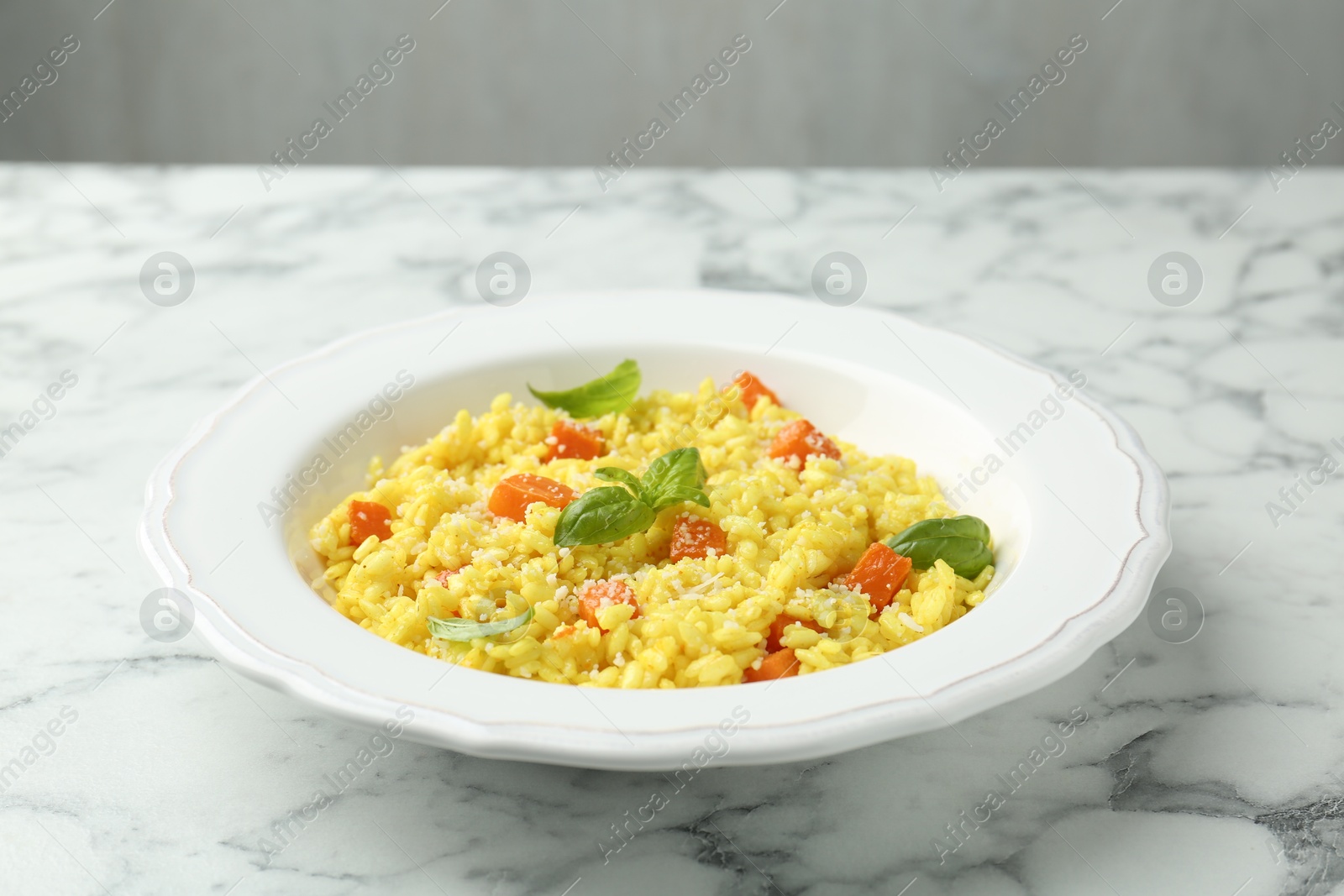 Photo of Delicious pumpkin risotto on white marble table, closeup