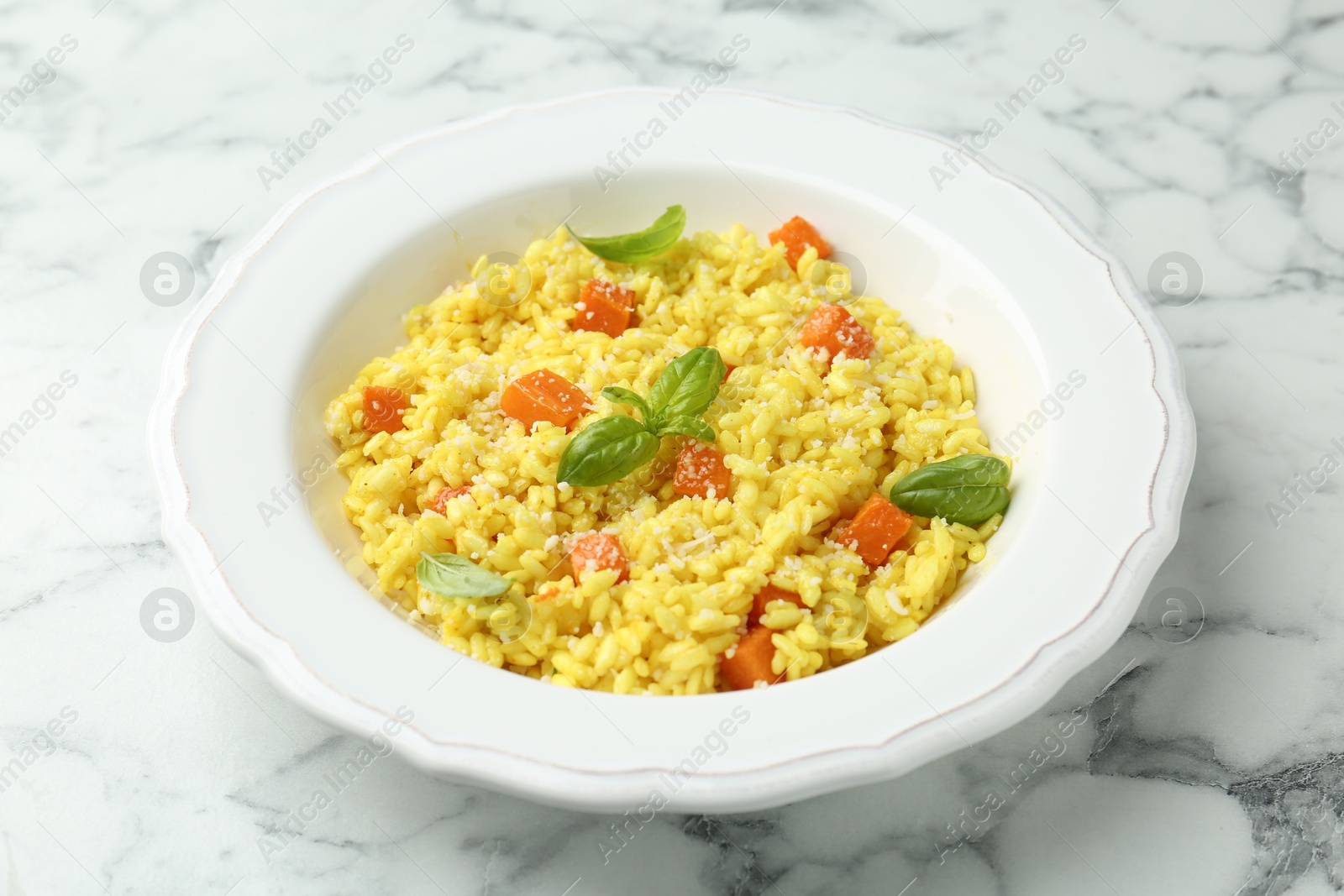 Photo of Delicious pumpkin risotto on white marble table, closeup