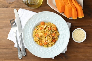 Photo of Delicious pumpkin risotto served on wooden table, flat lay