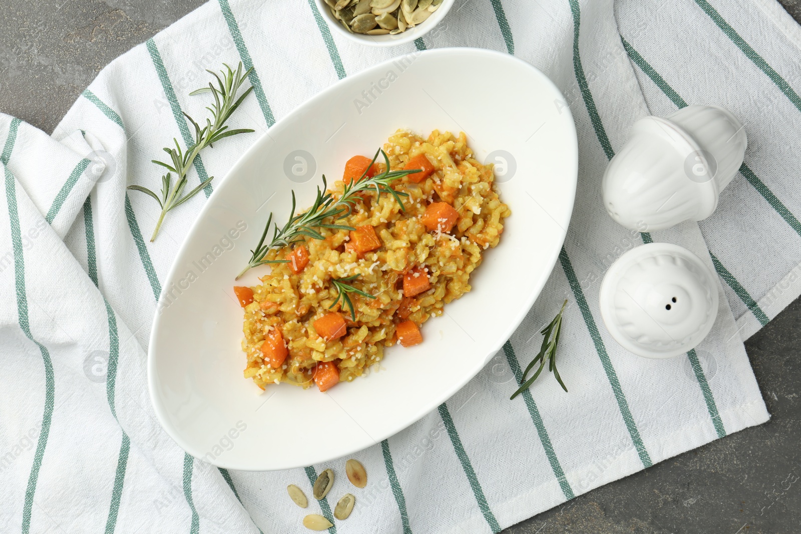 Photo of Delicious pumpkin risotto with rosemary on grey table, flat lay