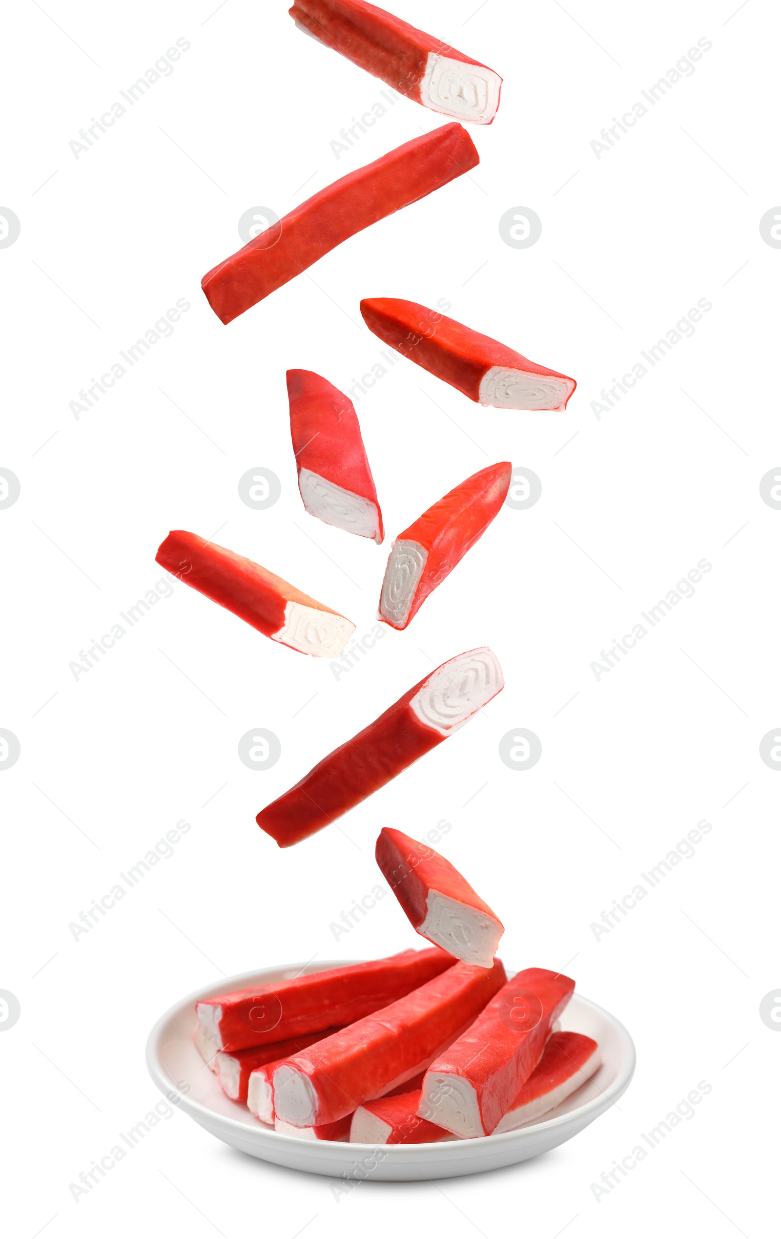 Image of Crab stick pieces falling onto plate on white background