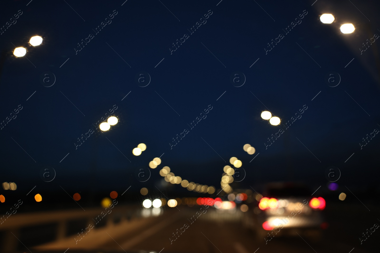 Photo of Blurred view of cityscape with road traffic and street lights in evening