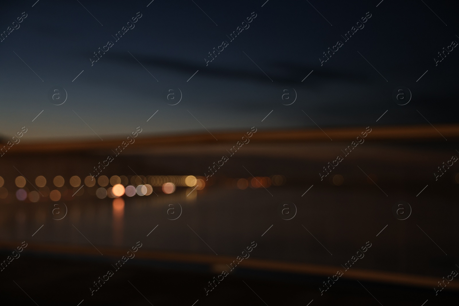 Photo of Blurred view of river and city street with lights in evening