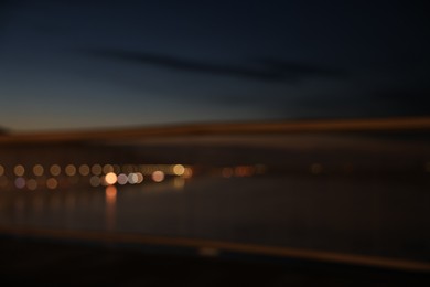 Photo of Blurred view of river and city street with lights in evening