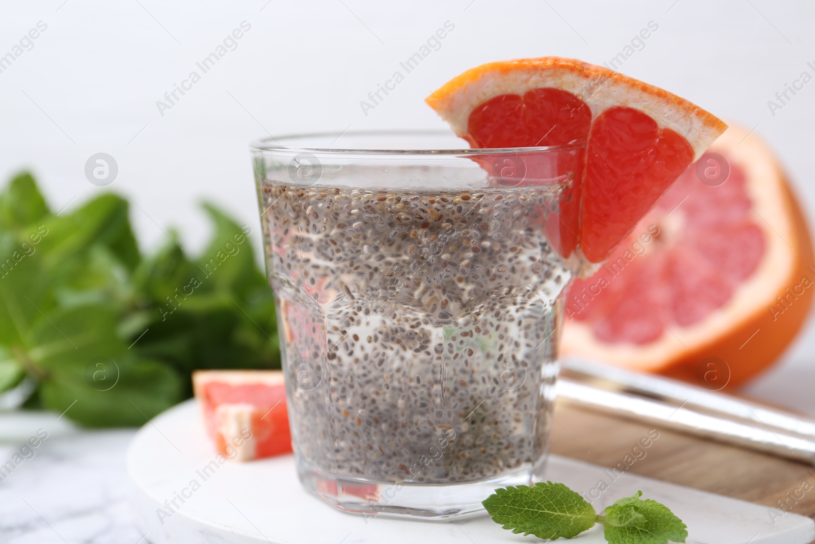 Photo of Glass of drink with chia seeds and grapefruit on white marble table, closeup