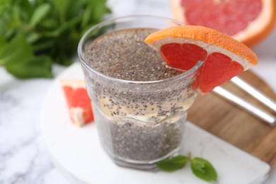 Photo of Glass of drink with chia seeds and grapefruit on white marble table, closeup