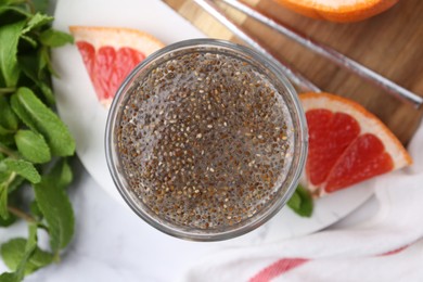 Photo of Glass of drink with chia seeds and grapefruit on white marble table, flat lay